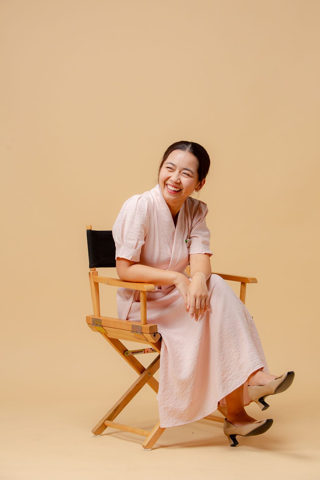 Belle, founder and lead wedding planner of BFF Wedding Project, laughing on a director's chair